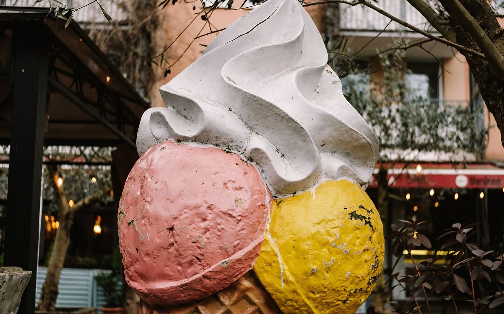 A vibrant outdoor sculpture of a giant ice cream cone with three scoops in a playful setting.